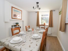A dining room with a table set for six people near a window with curtains at Pengraig near Tregaron