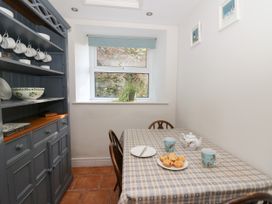 A dining area with a checkered tablecloth on the table muffins tea set mugs and a plant on the window sill at Pengraig near Tregaron