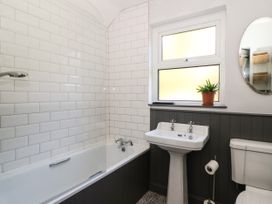 A bathroom with a bathtub shower sink toilet and a plant on the window at Pengraig near Tregaron