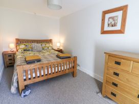 A bedroom with a wooden bed and matching bedside tables and dresser near Tregaron