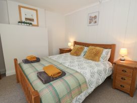A bedroom with a wooden double bed two bedside tables with lamps and framed pictures on the walls at Pengraig near Tregaron