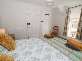 A bedroom with a bed with pillows and folded towels a wooden chair by a window with plaid curtains at Pengraig near Tregaron