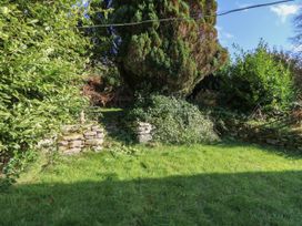 A garden area with grass, stone walls, and dense bushes near Tregaron