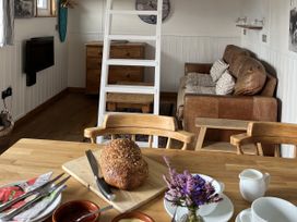 A living room with a dining table and a loaf of bread at Shepherds Cabin at Titterstone Clee Hill