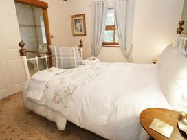 A bedroom with a white bed next to a window and an ensuite bathroom at Gelli Glud in Eglwysbach