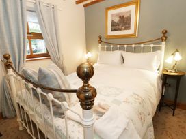A bedroom with a metal bed frame pillows bedside tables lamps and a framed picture on the wall at Gelli Glud in Eglwysbach