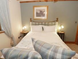 A bedroom with a bed white pillows bedside tables with lamps and a framed picture above the bed at Gelli Glud in Eglwysbach