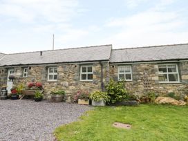 Stone cottage with slate roof and green door surrounded by plants and flowers at Gelli Glud in Eglwysbach
