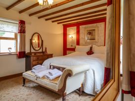 A bedroom with a bed and mirror at Gelli Glud in Eglwysbach