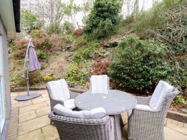 A table with chairs and an umbrella stand in an outdoor area at Gelli Glud in Eglwysbach