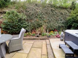 A garden with a table and chairs alongside a hot tub at Gelli Glud in Eglwysbach