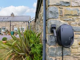 An electric vehicle charger mounted on a stone wall at Gelli Glud Eglwysbach