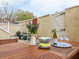 A wooden outdoor table with a vase of flowers bowls plates wine bottle and glasses in a patio area at Cottage 1 Newcourt Torquay