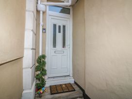 An entrance door with two glass panels a doormat a small spiral plant and a colorful bird decoration at Cottage 1 Newcourt in Torquay