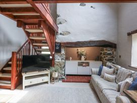 A living room with a staircase and a television at Cegin Foch in Chwilog