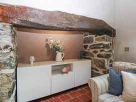 A living room with a stone wall and wooden beam at Cegin Foch in Chwilog