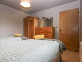 A bedroom with two beds and a wardrobe at Cegin Foch in Chwilog