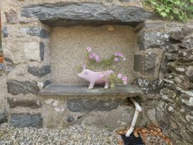 A pig planter with flowers on a stone shelf at Cegin Foch in Chwilog