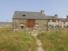 An exterior view of a stone house with a gravel path at Cegin Foch in Chwilog
