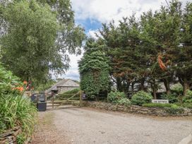 A gravel path leading to a gate with trees and a sign for An Skyber in Tideford