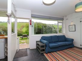 A snug with a sofa and door leading outside at 2 Brook Cottages in Hope Cove