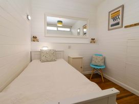 A bedroom with a single bed and a chair at 2 Brook Cottages in Hope Cove