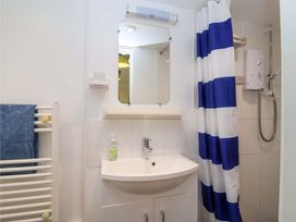 A bathroom with a sink, shower, and towel rail at 2 Brook Cottages in Hope Cove