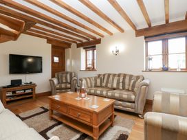 A living room with a sofa, coffee table, and television at Penrhiwarwydd Barn Pontywaun