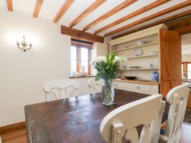 A dining room with a wooden table and chairs at Penrhiwarwydd Barn Pontywaun