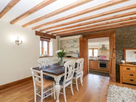 A dining room with a table and chairs leading to a kitchen at Penrhiwarwydd Barn Pontywaun