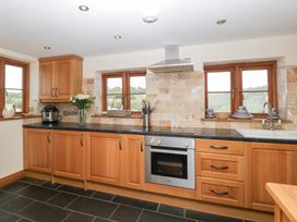 A kitchen with cabinets, sink, and stove at Penrhiwarwydd Barn in Pontywaun