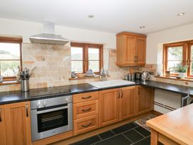 A kitchen with cabinets and a stove at Penrhiwarwydd Barn in Pontywaun