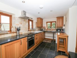 A kitchen with wooden cabinets and appliances at Penrhiwarwydd Barn Pontywaun