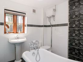 A bathroom with a bath tub, sink, and toilet at Penrhiwarwydd Barn in Pontywaun