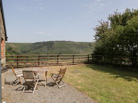 An outdoor seating area with a table and chairs overlooking a hill at Penrhiwarwydd Barn Pontywaun