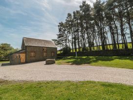 A house with a gravel driveway and trees at Penrhiwarwydd Barn Pontywaun
