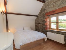 A bedroom with a bed and window at Penrhiwarwydd Barn Pontywaun