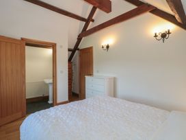 A bedroom with a bed, drawers, and an adjoining bathroom at Penrhiwarwydd Barn Pontywaun