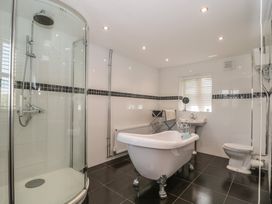 A bathroom with a shower, bathtub, sink, and toilet at Penrhiwarwydd Barn in Pontywaun