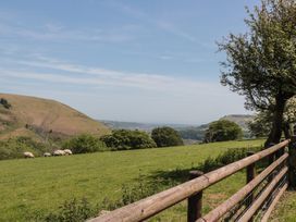 A field with sheep grazing and hills in the background at Penrhiwarwydd Barn Pontywaun