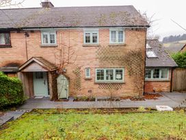 The back of a brick house with green framed windows a small covered porch and a garden with a grassy lawn at Hiraeth Cwmtaf near Cefn-Coed-Y-Cymmer