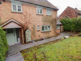 A brick house with green window frames and a door next to a wooden deck and garden at Hiraeth in Cwmtaf near Cefn-Coed-Y-Cymmer