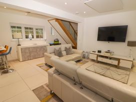 A living room with cream sofas a glass coffee table a wall mounted television and a sideboard under a window at Hiraeth in Cwmtaf near Cefn-Coed-Y-Cymmer