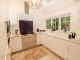 A kitchen with white cabinets a stove under a hood and a window above a sink at Hiraeth in Cwmtaf near Cefn-Coed-Y-Cymmer