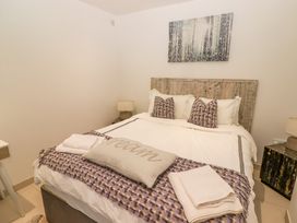 A bedroom with a bed with pillows and folded towels a side table with a lamp and a forest painting on the wall at Hiraeth in Cwmtaf near Cefn-Coed-Y-Cymmer