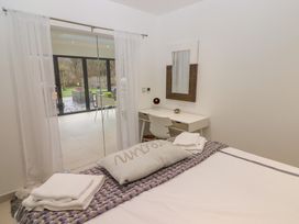 A bedroom with a bed folded towels a desk a chair a mirror and glass sliding doors leading outside at Hiraeth in Cwmtaf near Cefn-Coed-Y-Cymmer