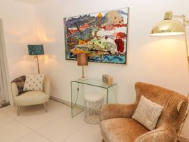 A sitting area with two armchairs a glass side table with a lamp and radio and a painting on the wall at Hiraeth in Cwmtaf near Cefn-Coed-Y-Cymmer