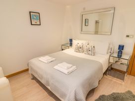 A bedroom with a bed with gray quilt and white towels on it two bedside tables with blue lamps and a large mirror on the wall at Hiraeth in Cwmtaf near Cefn-Coed-Y-Cymmer