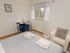 A bedroom with a bed with folded towels a blue chair a small desk and a white armchair with a cushion at Hiraeth in Cwmtaf near Cefn-Coed-Y-Cymmer