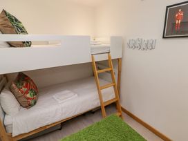A bunk bed with pillows and towels a ladder a green rug and a framed picture on the wall at Hiraeth in Cwmtaf near Cefn-Coed-Y-Cymmer